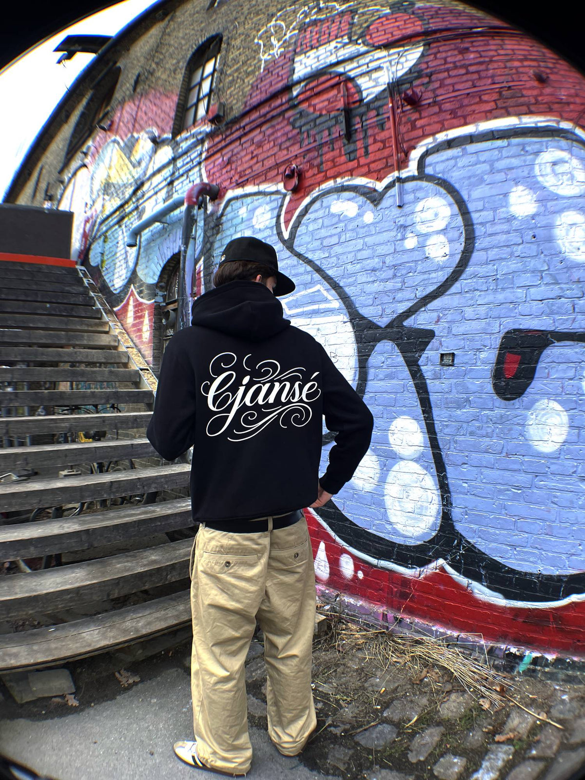 Model i hoodie med print på ryggen, sort boxy hoodie med stort ejansescript på ryggen, let cropped pasform